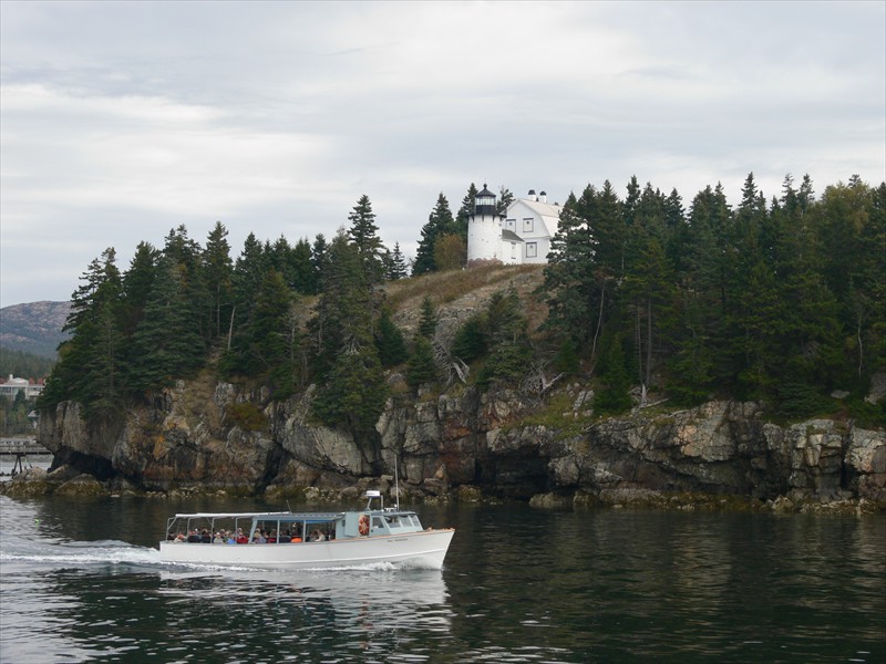 A tour boat goes past a lighthouse